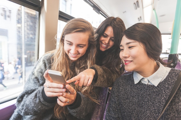 Drei frauen suchen ein smartphone im bus