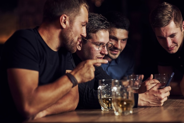 Drei Freunde ruhen sich in der Kneipe mit Bier in der Hand aus