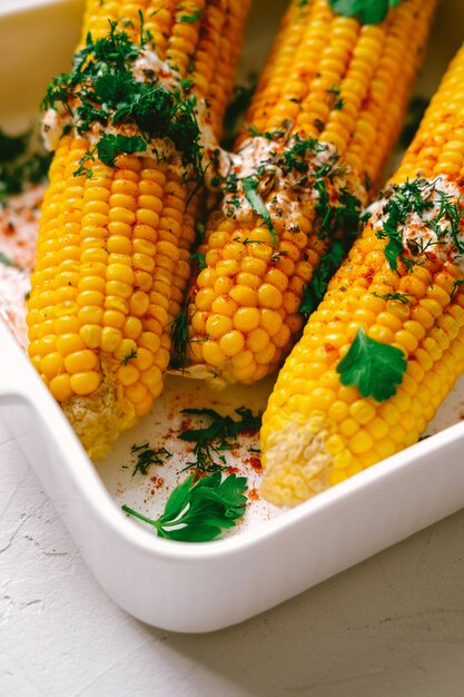 Foto drei gegrillte maiskolben mit sauce bedeckt