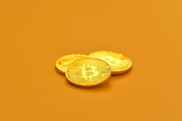 Drei gelbe Bitcoin-Bohnen, die auf einer flachen Oberfläche liegen