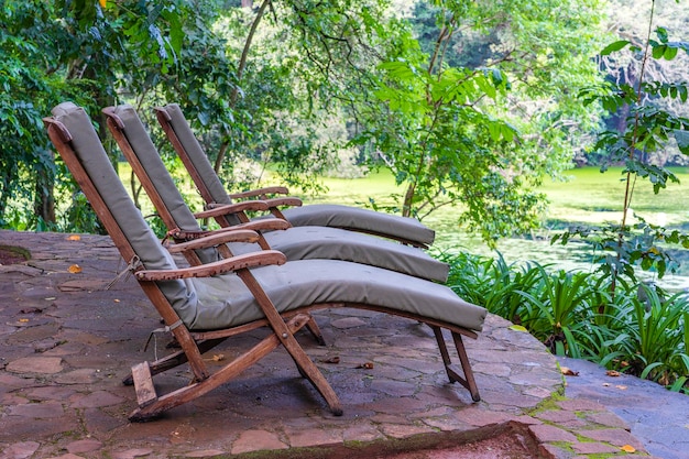 Drei gemütliche Sonnenliegen auf der tropischen Gartenterrasse Tansania Afrika hautnah