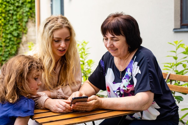 Drei Generationen von Frauen sitzen auf der Terrasse des Cafés im Freien