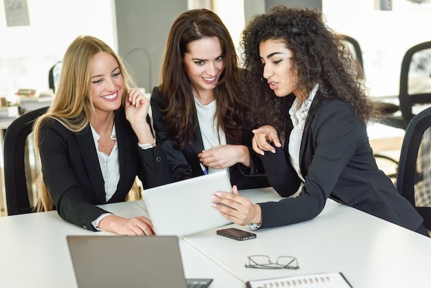 Drei Geschäftsfrauen, die in einem modernen Büro zusammenarbeiten