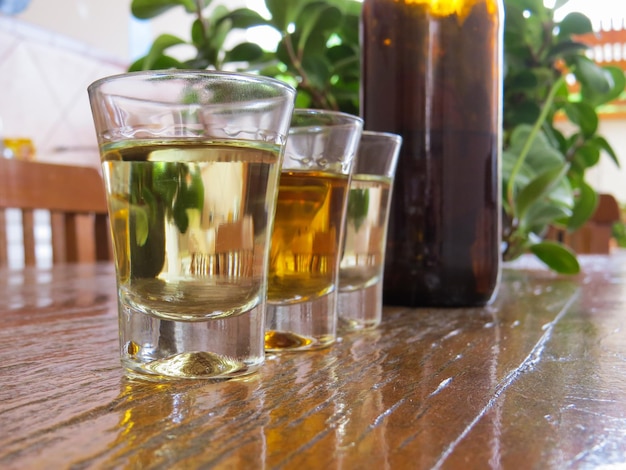 Drei Gläser Cachaca und eine Flasche auf Holztisch