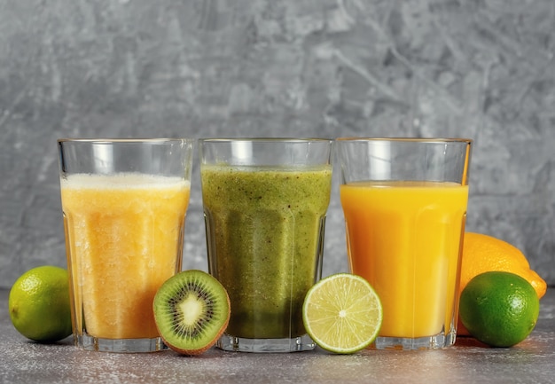 Drei Gläser hintereinander mit Orangensaft und Bananen-Orangen-Kiwi-Smoothie