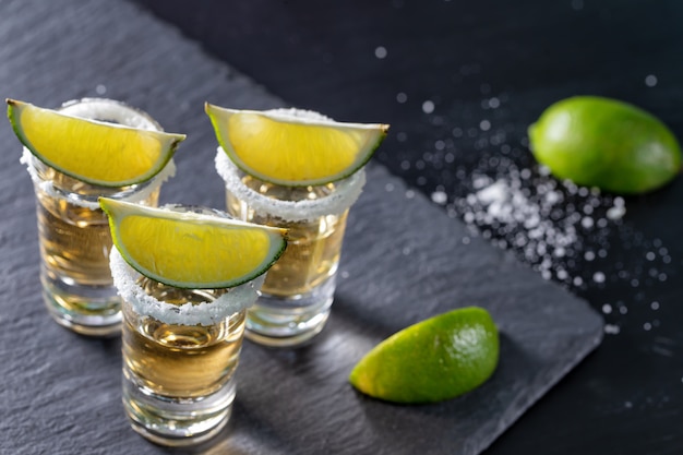 Drei Gläser mexikanischer Tequila und Kalk