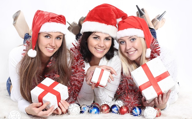 Drei glückliche junge Frauen im Kostüm des Weihnachtsmannes mit Weihnachtsgeschenken