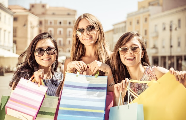 Drei glückliche Mädchen, die Spaß haben und einkaufen