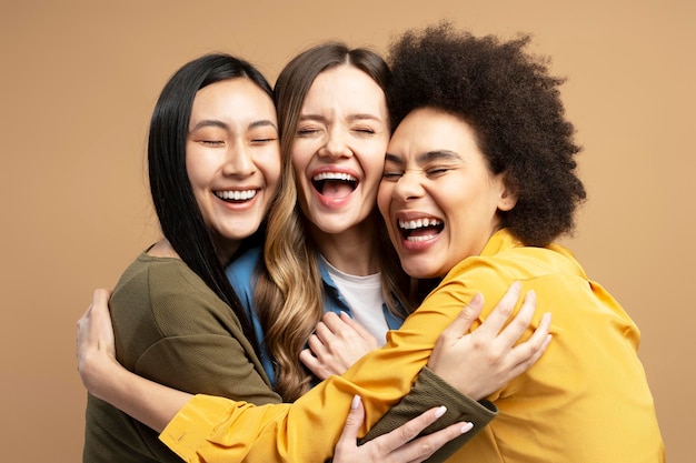 Drei glückliche, multiethnische Frauen, die sich umarmen und zusammen lachen