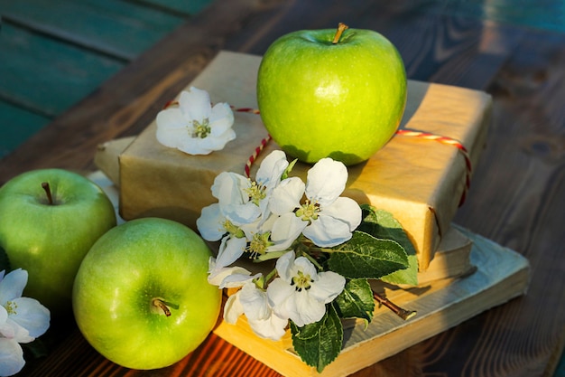 Drei grüne Äpfel und Blumen auf einer hölzernen Hintergrunderntesaison