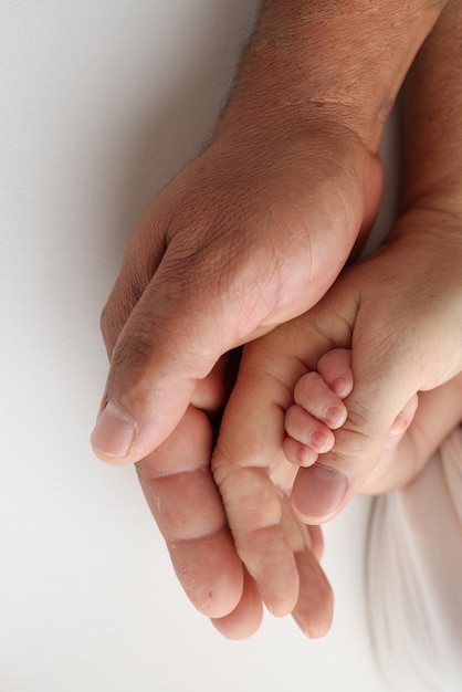 Drei Handflächen einer glücklichen Familie. Kleine neugeborene Hand mit winzigen Fingern. Die Handfläche von Eltern, Vater und Mutter hält den Griff eines Neugeborenen. Studio-Makroaufnahme auf weißem Hintergrund