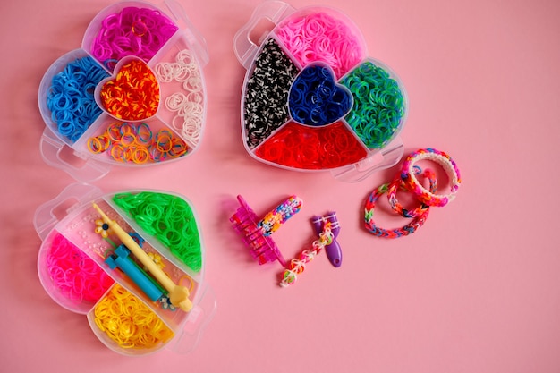 Drei herzförmige Behälter gefüllt mit farbigen Gummibändern zum Weben von Armbändern