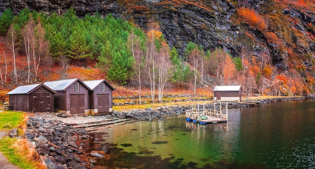 Drei Holzhütten am Ufer eines Fjords