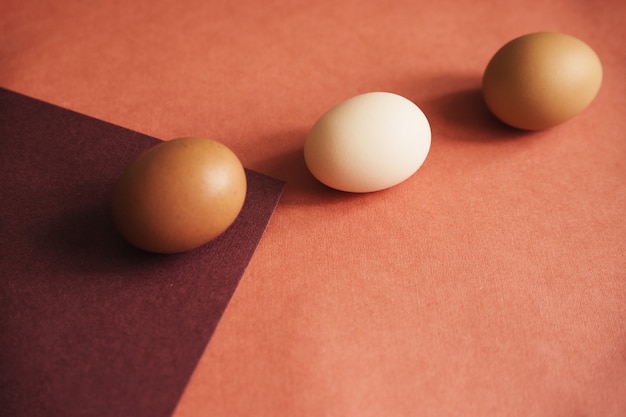 Drei Hühnereier werden auf Papier in Naturfarben gelegt. Die Textur des Papiers und des Eies ist beige.