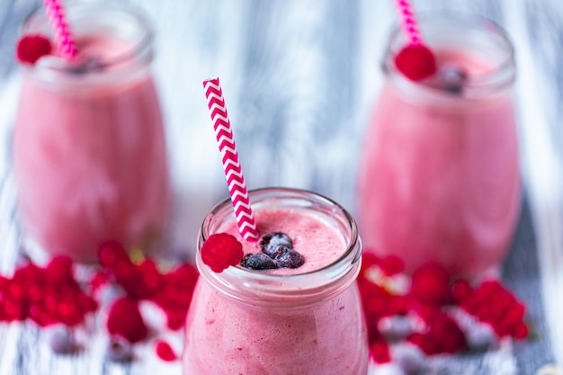 Drei Joghurt-Smoothie mit Cranberry-Himbeer-Blaubeere auf Holztisch in Gläsern Selektiver Fokus