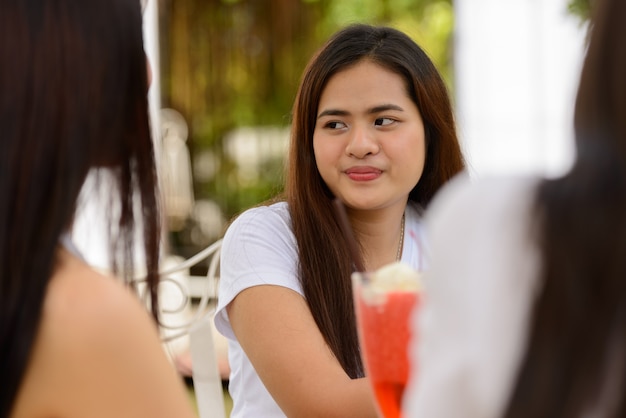 Drei junge asiatische Frauen als Freunde, die zusammen im Café draußen entspannen