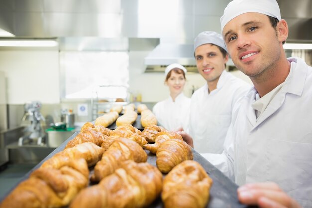 Drei junge Bäcker, die in einer Bäckerei aufwerfen