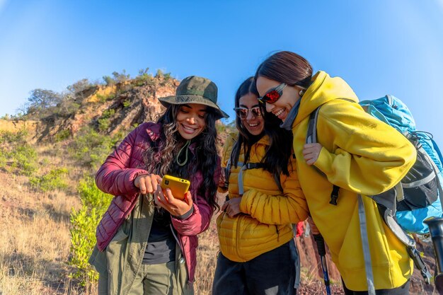 Drei junge Frauen beenden ihre Wanderung, um ihr GPS-Handy zu überprüfen und genießen die Freiheit