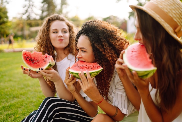 Drei junge Frauen haben Spaß zusammen und essen Wassermelone an heißen Sommertagen