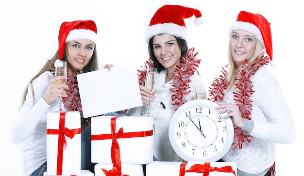 Drei junge Frauen in den Hüten von Weihnachtsmann mit Weihnachtsgeschenken f