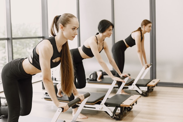 Drei junge Frauen trainieren im Fitnessstudio. Frauen, die schwarze Sportkleidung tragen. Kaukasische Mädchen trainieren mit Ausrüstung.