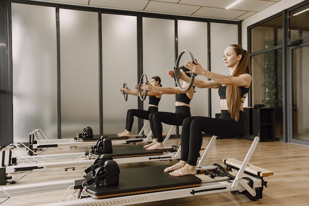 Drei junge Frauen trainieren im Fitnessstudio. Frauen, die schwarze Sportkleidung tragen. Kaukasische Mädchen trainieren mit Ausrüstung.