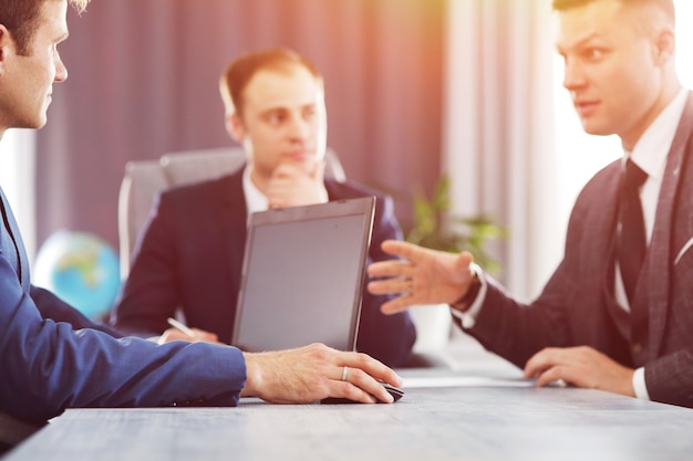 Drei junge Geschäftsleute treffen sich im Büro und besprechen gemeinsam eine wichtige Idee