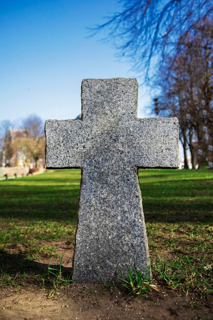 Foto drei katholische steinkreuze, die in einer reihe vor dem hintergrund eines kopfsteinpflasterzauns in einem park an einem sonnigen tag stehen, eine heilige beerdigung auf einem christlichen friedhof, monolithische religiöse denkmäler