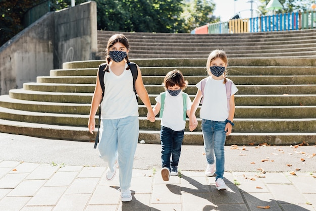 Drei kaukasische Brüder unterschiedlichen Alters gehen zu Beginn des Jahres mit Masken im Gesicht wegen der Covid19-Coronavirus-Pandemie zur Schule