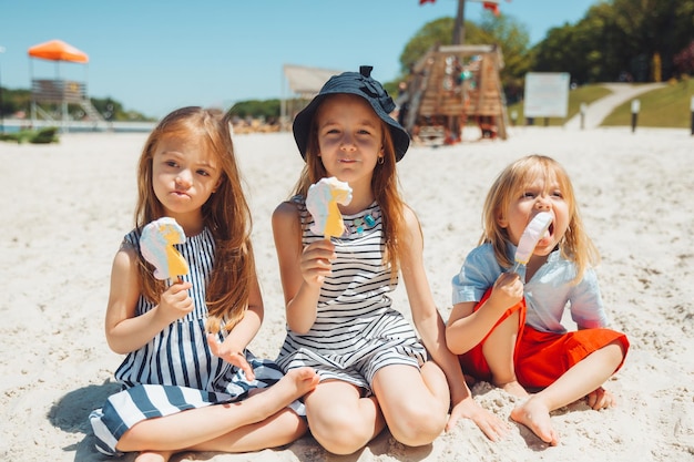 Drei Kinder essen Eis am Strand, ein Kind mit Down-Syndrom führt ein normales Leben