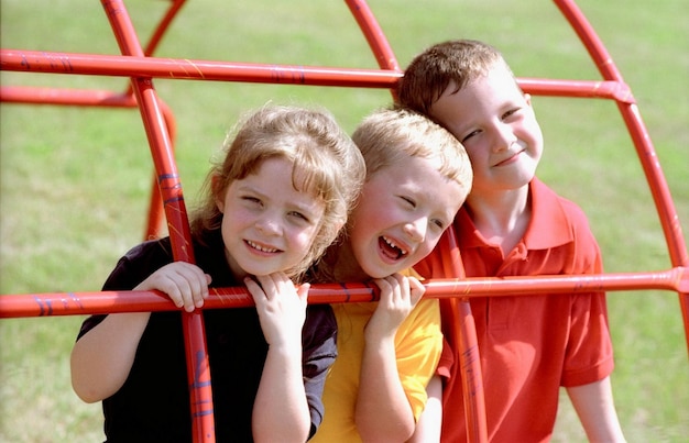 Foto drei kinder lächeln auf einem spielplatz