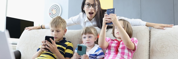 Drei Kinder sitzen mit Smartphones in der Hand auf der Couch