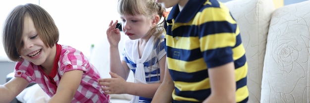 Drei Kinder spielen Brettspiel, ein Mädchen sitzt und weint