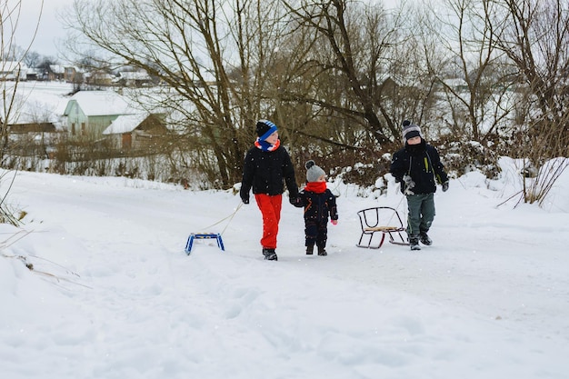 Drei Kinder ziehen Schlitten in den Berg