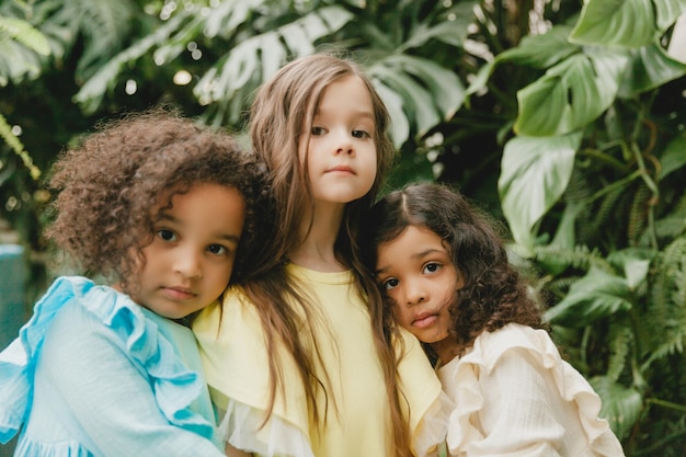 Drei kleine Mädchen im Garten mit Blumen in ihren Händen Kinder verschiedener Nationalitäten