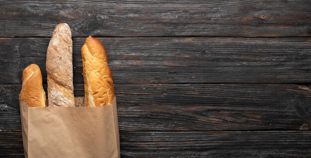 Drei knusprige französische Baguettes auf einem hölzernen Hintergrund in einem Papiertütenblick von oben