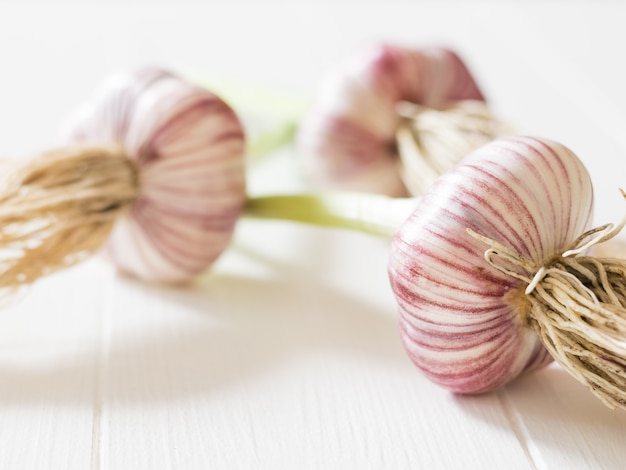 Drei Köpfe frischer, großer Knoblauch auf einem weißen Tisch. Gesunde natürliche Gewürze. Bestandteil der traditionellen Medizin.