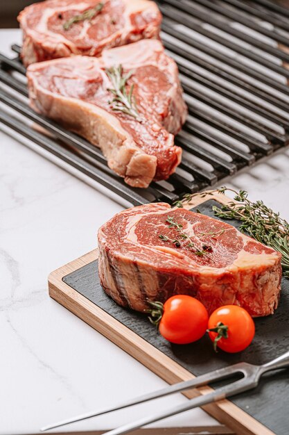 Drei köstliche Steaks bereit zum Grillen auf einer weißen Marmoroberfläche