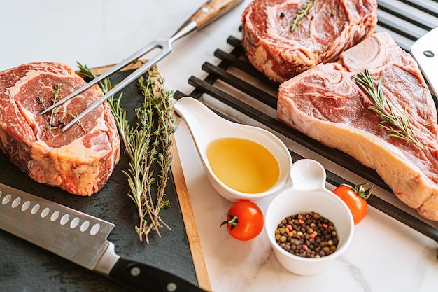 Drei köstliche Steaks bereit zum Grillen auf einer weißen Marmoroberfläche