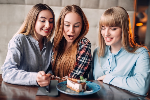 Drei lächelnde Küken essen süße Kuchen im Café