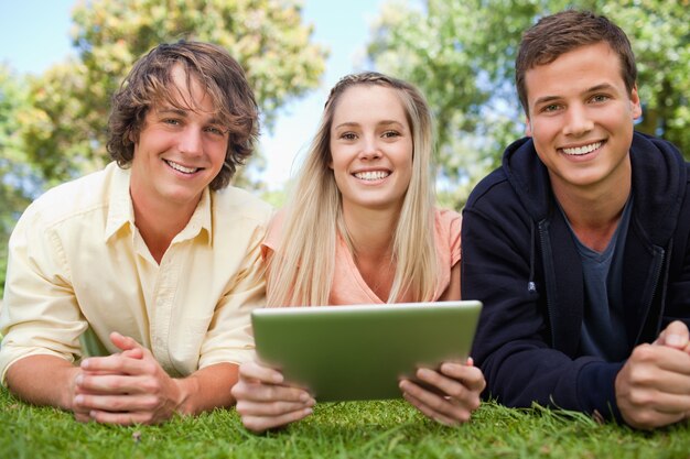 Drei lächelnde Studenten, die eine Tasttablette verwenden