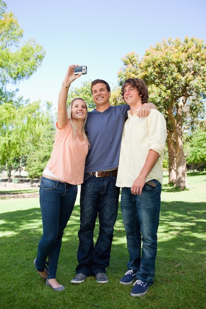 Drei lächelnde Studenten, die Fotos von selbst machen