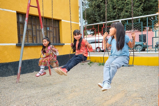 Foto drei lateinamerikanische mädchen spielen auf einer schaukel im freien in la paz, bolivien