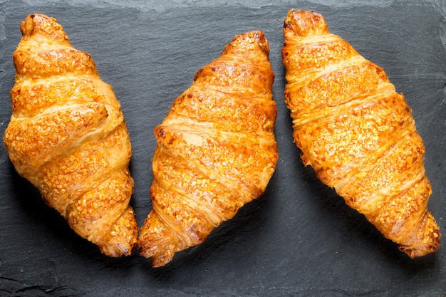 Drei leckere Croissants auf schwarzem Steinhintergrund französisches Essen hautnah