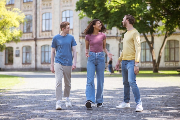 Drei Leute gehen im Park spazieren und diskutieren etwas