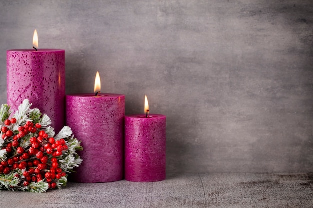 Drei lila Kerzen auf grauem Hintergrund, Weihnachtsdekoration. Adventsstimmung.