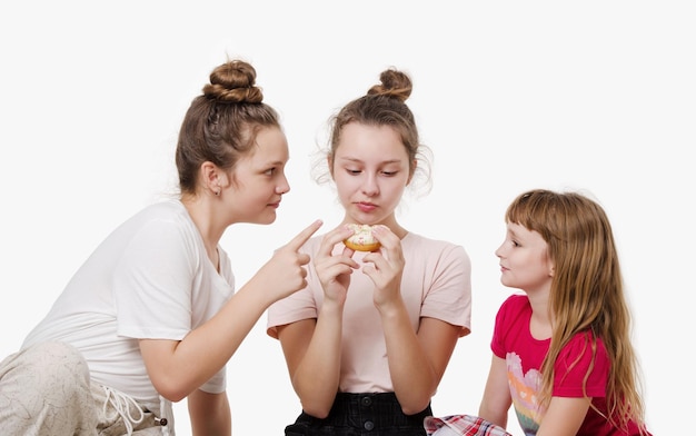 Drei Mädchen, die Krapfen essen und lächeln Studioportrait auf weißem Hintergrund