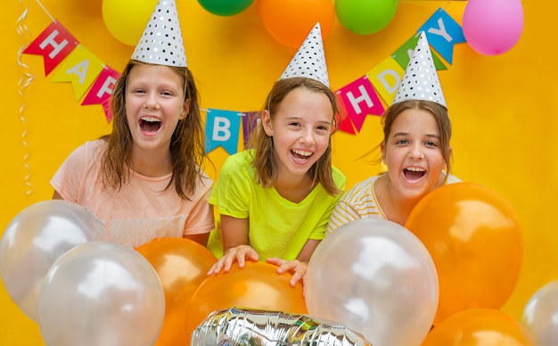 Drei Mädchen mit Bällen auf gelbem Grund. Kinder auf der Geburtstagsfeier