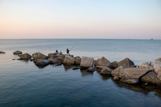 Drei Männer angeln auf dem Meer. Angeln während der Feiertage. Tiefblaues Wasser, angenehme Morgendämmerung