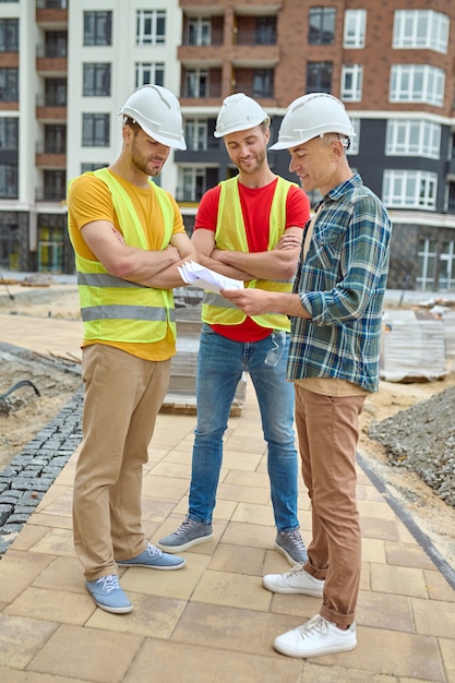 Foto drei männer in schutzhelmen analysieren technische zeichnungen